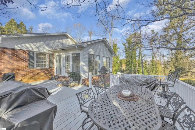 wooden terrace featuring area for grilling and outdoor dining space