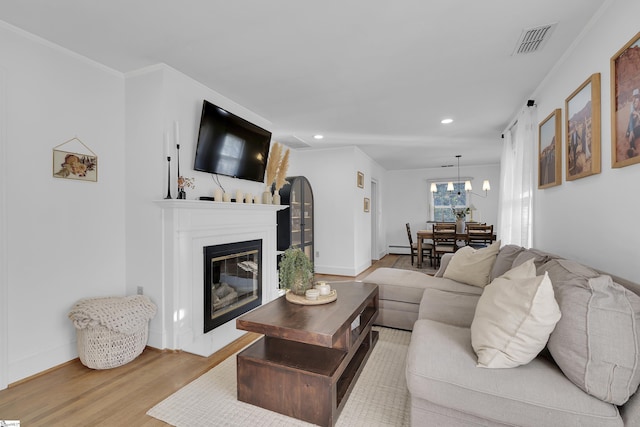 living room featuring baseboards, visible vents, a glass covered fireplace, wood finished floors, and recessed lighting