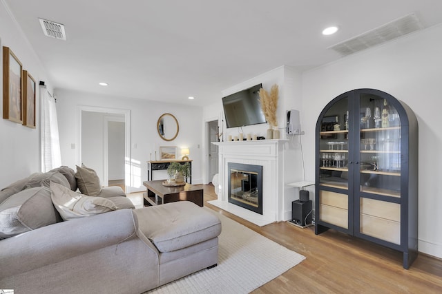 living area with recessed lighting, visible vents, wood finished floors, and a glass covered fireplace