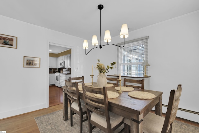 dining room featuring baseboards, ornamental molding, wood finished floors, an inviting chandelier, and baseboard heating