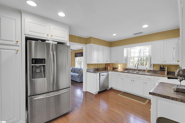 kitchen with dark countertops, visible vents, appliances with stainless steel finishes, a sink, and plenty of natural light