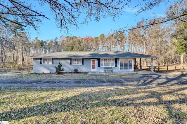 view of front of house featuring a carport, fence, and driveway