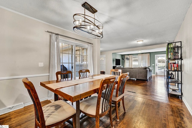 dining area with baseboards, visible vents, hardwood / wood-style floors, a textured ceiling, and a notable chandelier