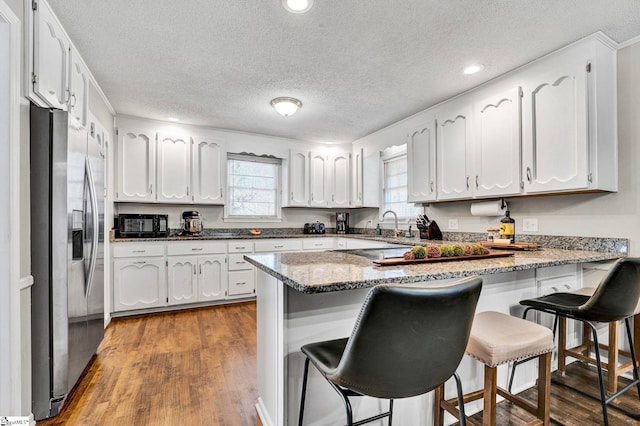 kitchen with white cabinets, stainless steel fridge, and a peninsula