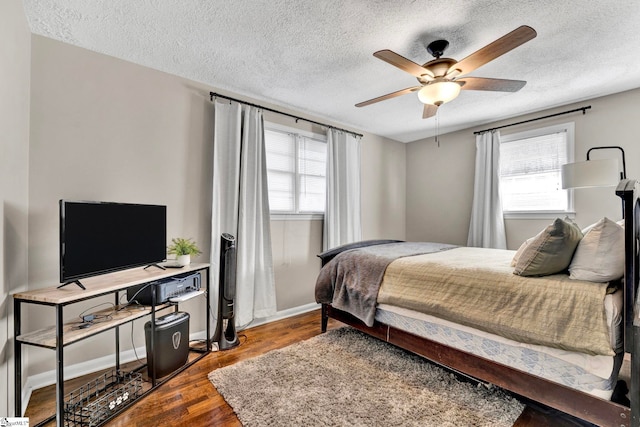 bedroom with a ceiling fan, multiple windows, a textured ceiling, and wood finished floors