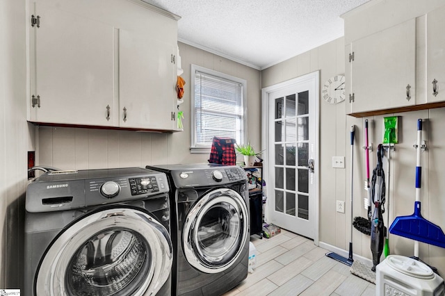 laundry area featuring a textured ceiling, ornamental molding, cabinet space, wood tiled floor, and washing machine and clothes dryer