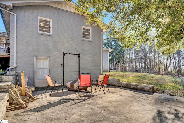 back of house featuring a patio, brick siding, a lawn, and fence