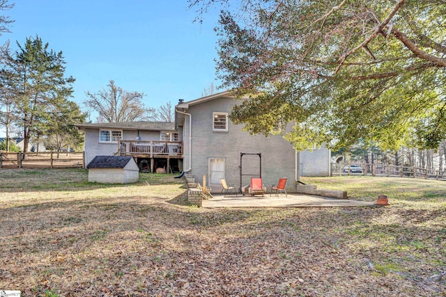 rear view of property featuring an outbuilding, a patio, a storage unit, a fenced backyard, and a wooden deck