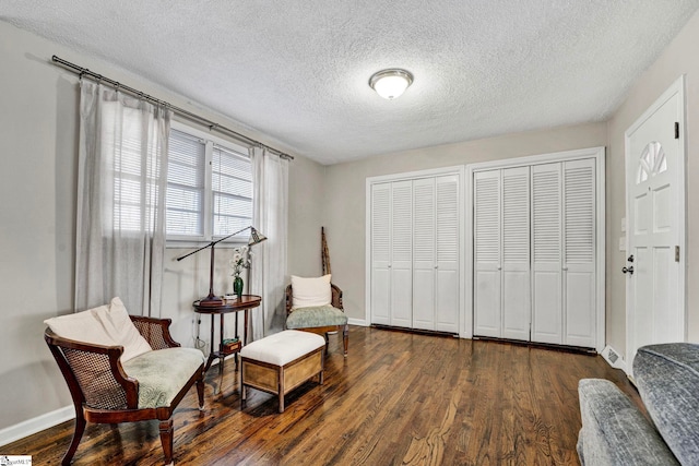 living area featuring a textured ceiling, wood finished floors, and baseboards