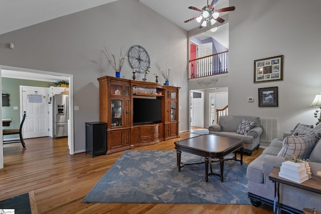 living area featuring a ceiling fan, visible vents, high vaulted ceiling, and wood finished floors