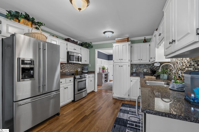 kitchen featuring stainless steel appliances, white cabinets, a sink, and ornamental molding