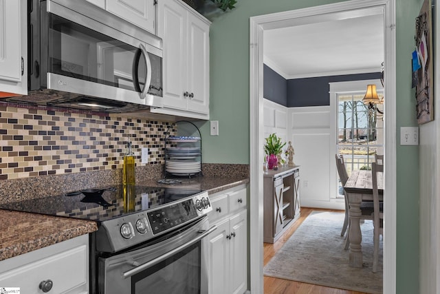 kitchen featuring crown molding, stainless steel appliances, backsplash, white cabinetry, and light wood-type flooring