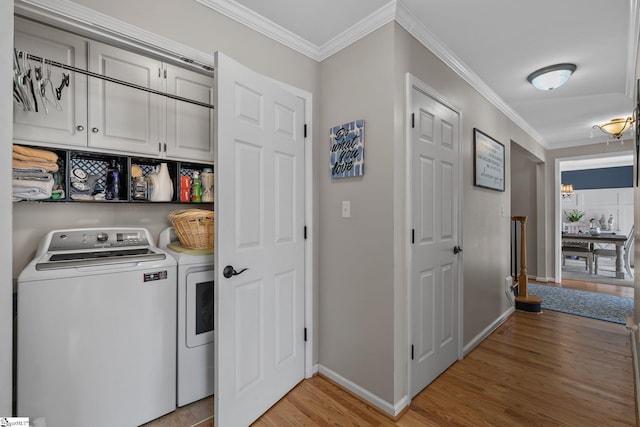 washroom with cabinet space, baseboards, ornamental molding, washer and dryer, and light wood-type flooring