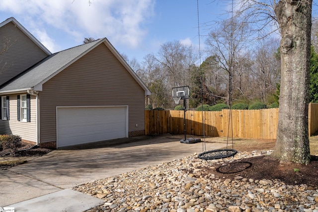 view of side of property with a garage, concrete driveway, and fence