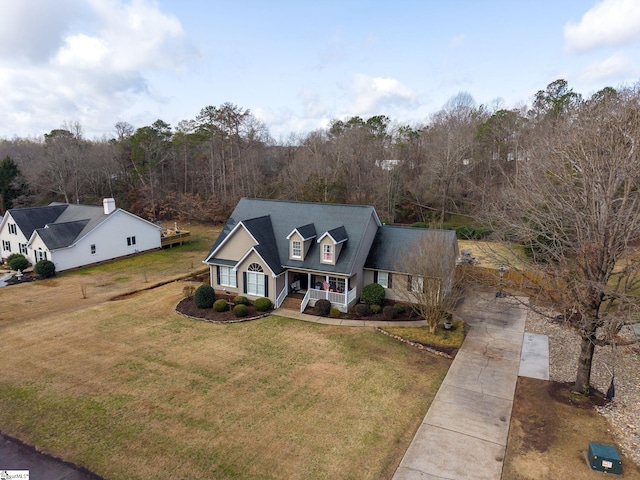 view of front of house featuring a front lawn, a porch, and a view of trees