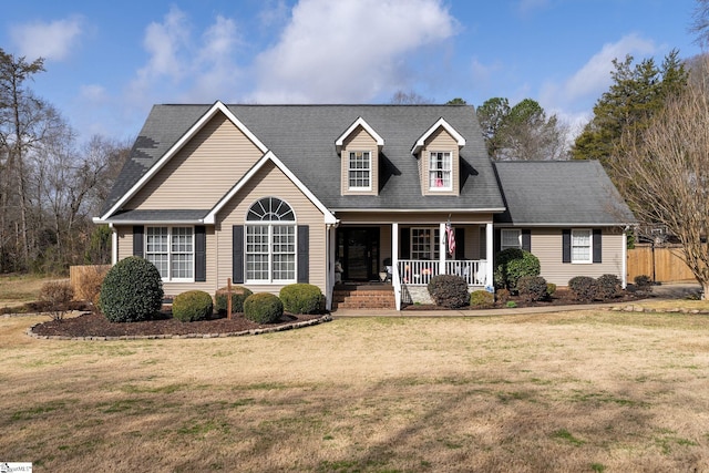 cape cod house with covered porch, a shingled roof, and a front lawn