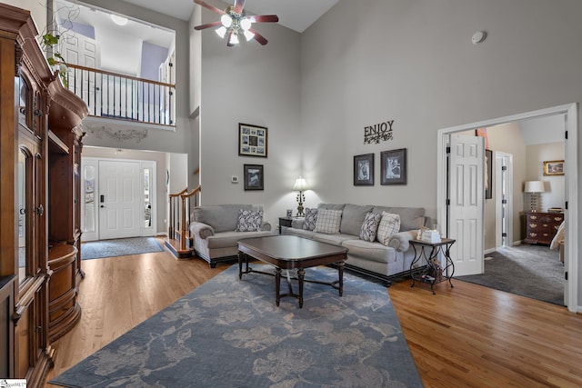 living room featuring stairway, wood finished floors, a ceiling fan, and baseboards