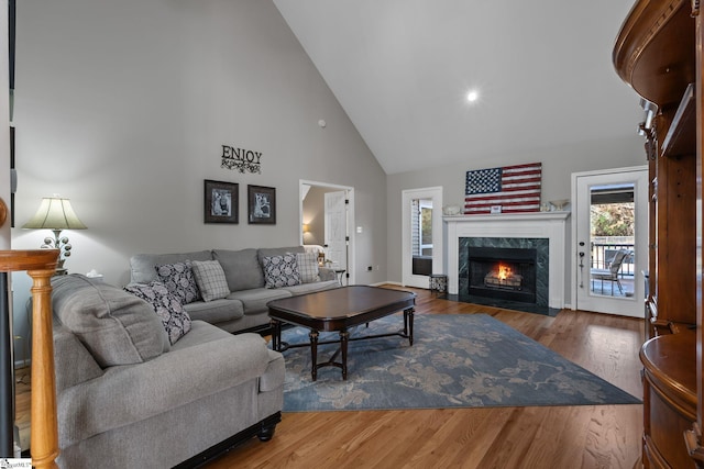 living room with baseboards, a fireplace, high vaulted ceiling, and wood finished floors