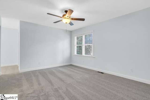 empty room with ceiling fan, carpet floors, visible vents, and baseboards