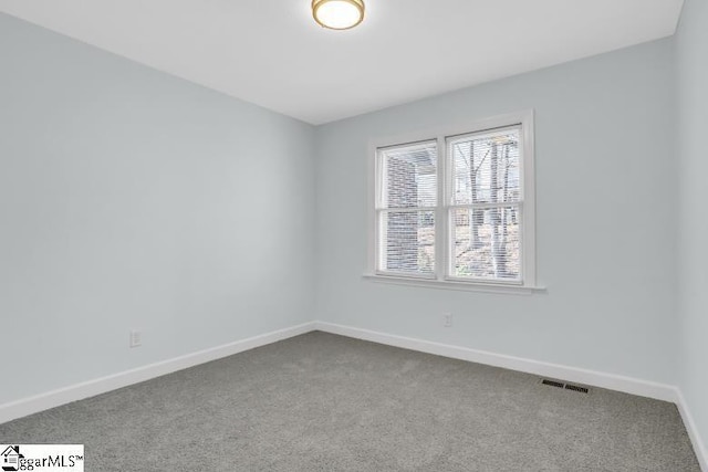 empty room with carpet flooring, visible vents, and baseboards