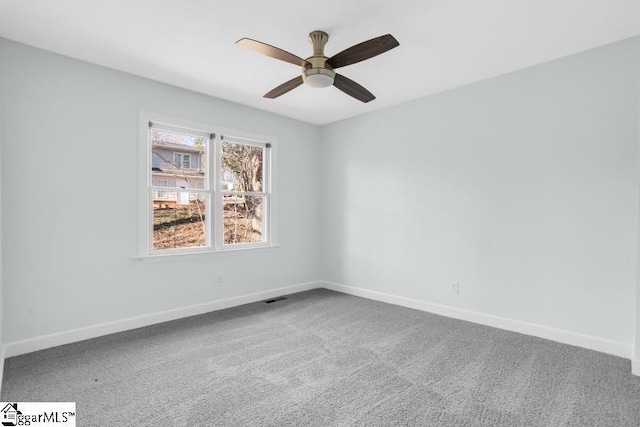 carpeted spare room featuring visible vents, ceiling fan, and baseboards