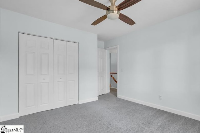 unfurnished bedroom featuring carpet floors, a closet, baseboards, and a ceiling fan