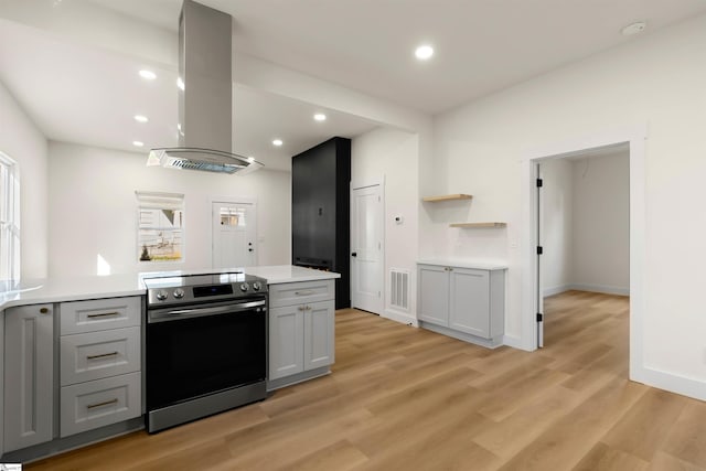 kitchen featuring island exhaust hood, gray cabinets, light countertops, visible vents, and stainless steel range with electric stovetop