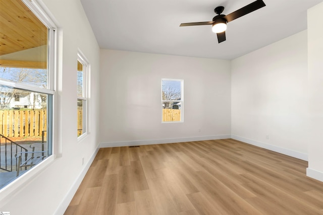 empty room featuring ceiling fan, plenty of natural light, baseboards, and light wood-style flooring