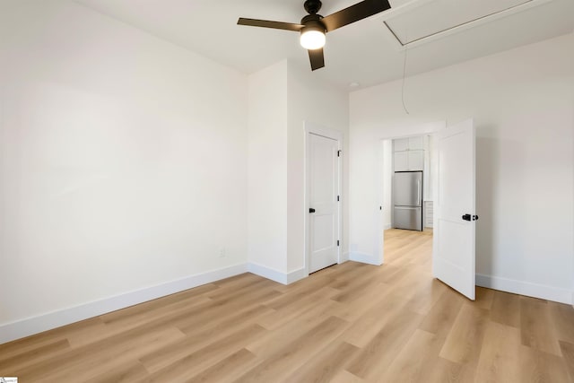 unfurnished bedroom featuring stainless steel fridge, attic access, baseboards, a ceiling fan, and light wood-type flooring