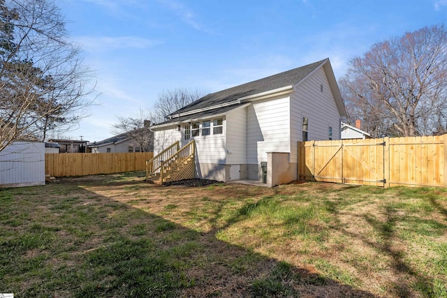 rear view of house with a yard, an outdoor structure, and a fenced backyard