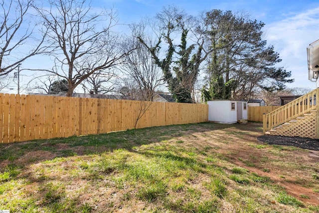 view of yard with an outbuilding, a storage shed, stairway, and a fenced backyard