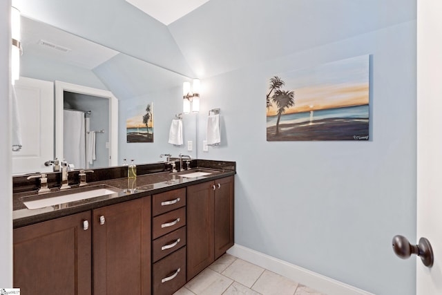 bathroom featuring vaulted ceiling, a sink, baseboards, and double vanity