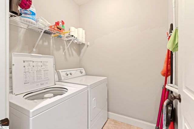 clothes washing area with laundry area, washer and clothes dryer, baseboards, and light tile patterned floors