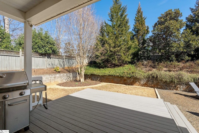 wooden deck with area for grilling, a water view, and fence