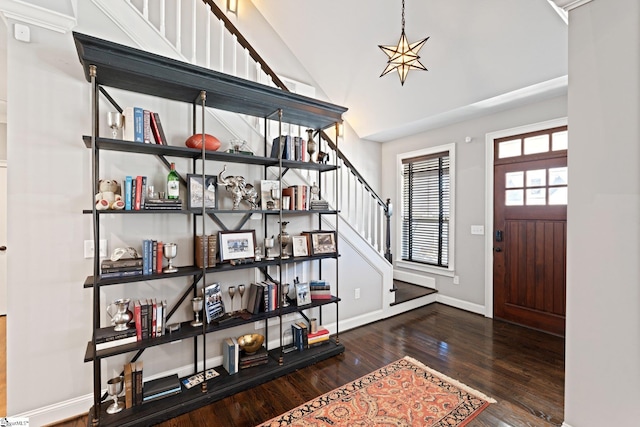 entrance foyer featuring a notable chandelier, wood finished floors, baseboards, stairs, and vaulted ceiling