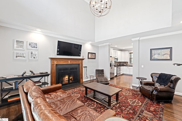 living area with crown molding, dark wood-style flooring, and a lit fireplace