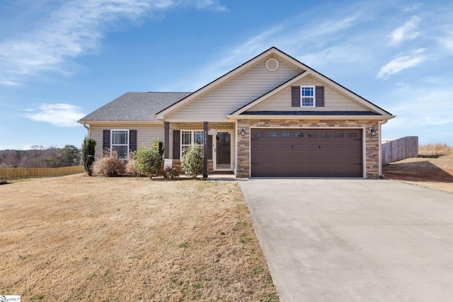 view of front facade featuring stone siding, concrete driveway, fence, and a front lawn