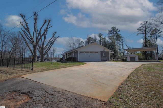 view of side of home featuring an outbuilding, an attached garage, fence, concrete driveway, and a lawn