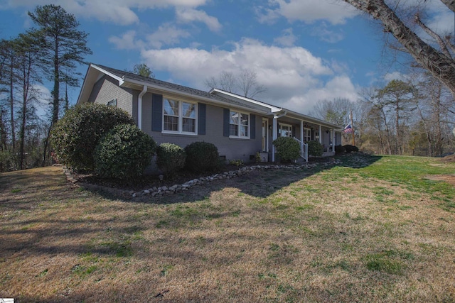 ranch-style home featuring a front yard, covered porch, and brick siding