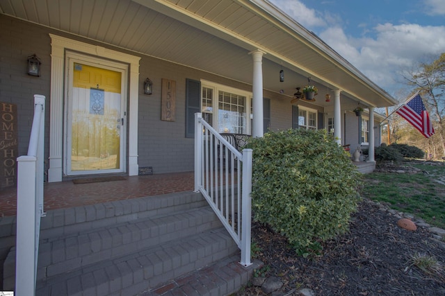 property entrance featuring covered porch and brick siding