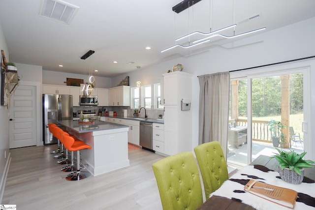 kitchen featuring appliances with stainless steel finishes, visible vents, a kitchen island, and tasteful backsplash