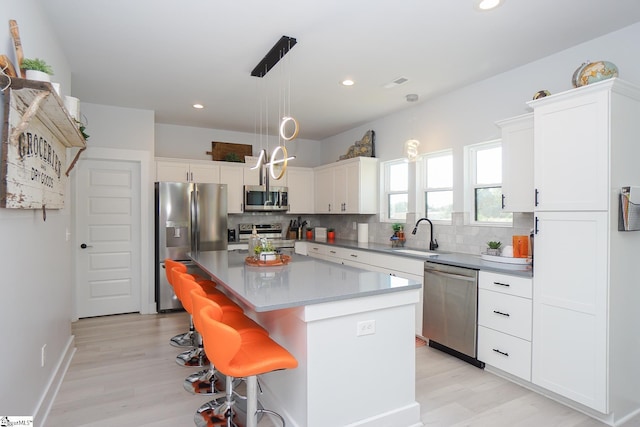 kitchen with stainless steel appliances, white cabinetry, a sink, and decorative backsplash