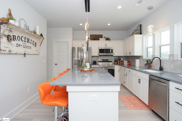 kitchen featuring appliances with stainless steel finishes, a kitchen bar, a sink, and decorative backsplash