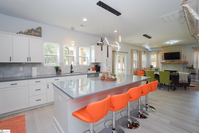 kitchen with a sink, a kitchen island, a kitchen breakfast bar, open floor plan, and decorative backsplash