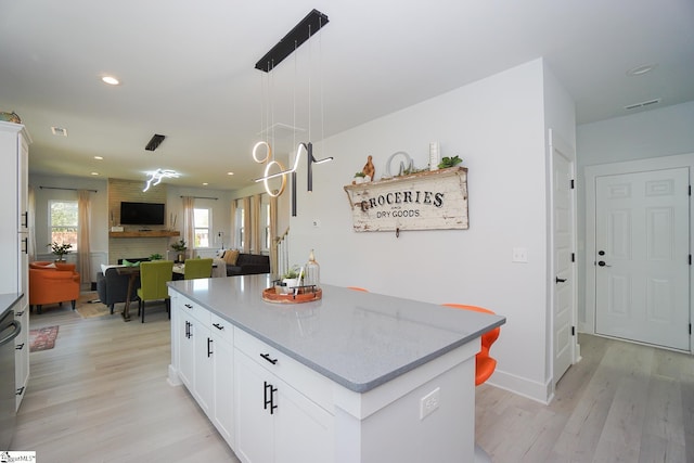 kitchen featuring open floor plan, a fireplace, visible vents, and light wood-style floors