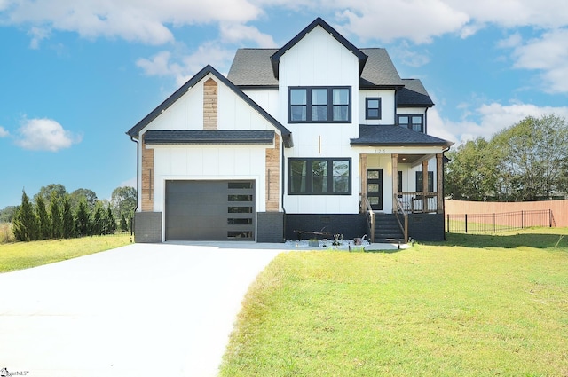 view of front of house with a garage, fence, concrete driveway, board and batten siding, and a front yard