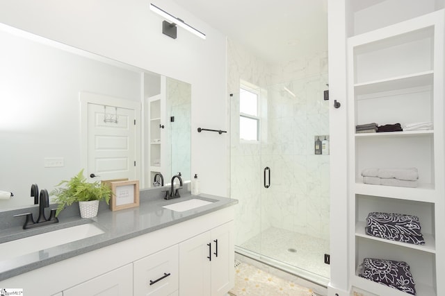 bathroom featuring double vanity, a stall shower, a sink, and a walk in closet