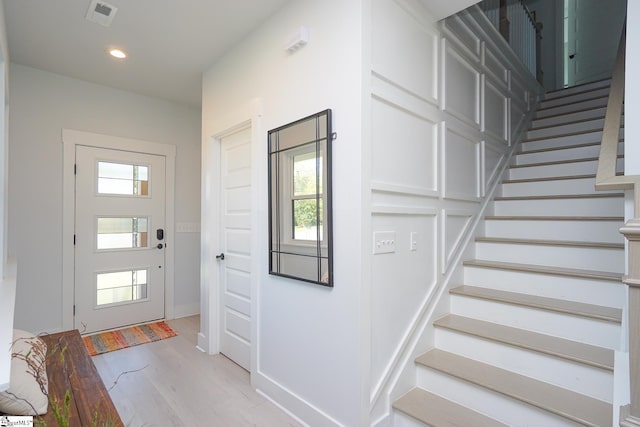 foyer featuring light wood finished floors, plenty of natural light, stairs, and recessed lighting