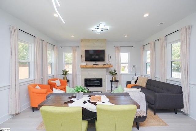 living area with a decorative wall, a fireplace, light wood-style flooring, and recessed lighting