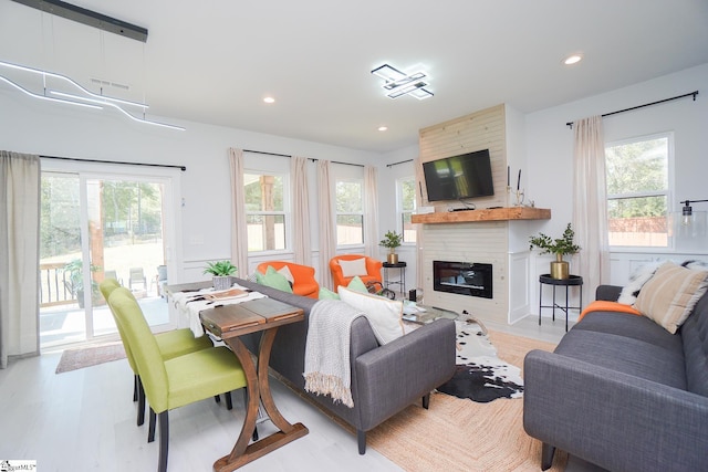 living room featuring recessed lighting, a fireplace, light wood-style flooring, and a healthy amount of sunlight